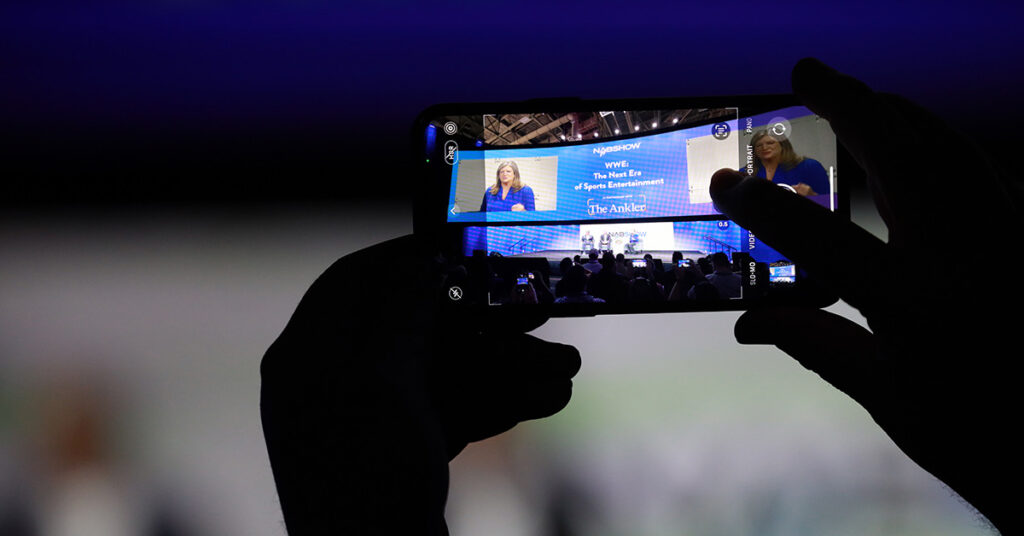 Someone in the crowd is taking a photo of a sponsored session taking place on stage at NAB Show.