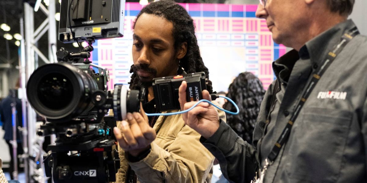 Two men are working a broadcast camera on the show floor. 